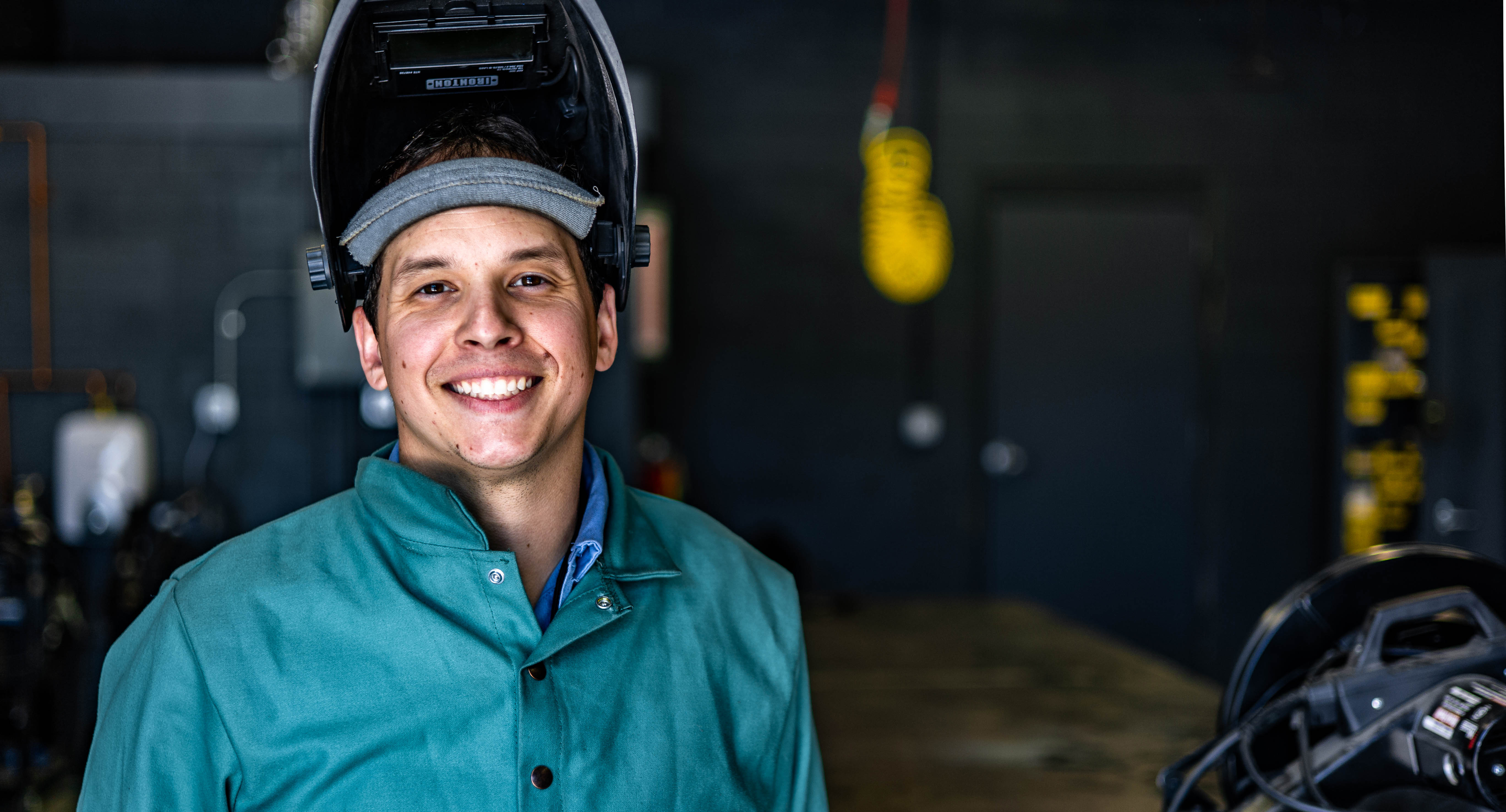 Alex Armata smiling wearing welding safety gear pictured in a welding workshop
