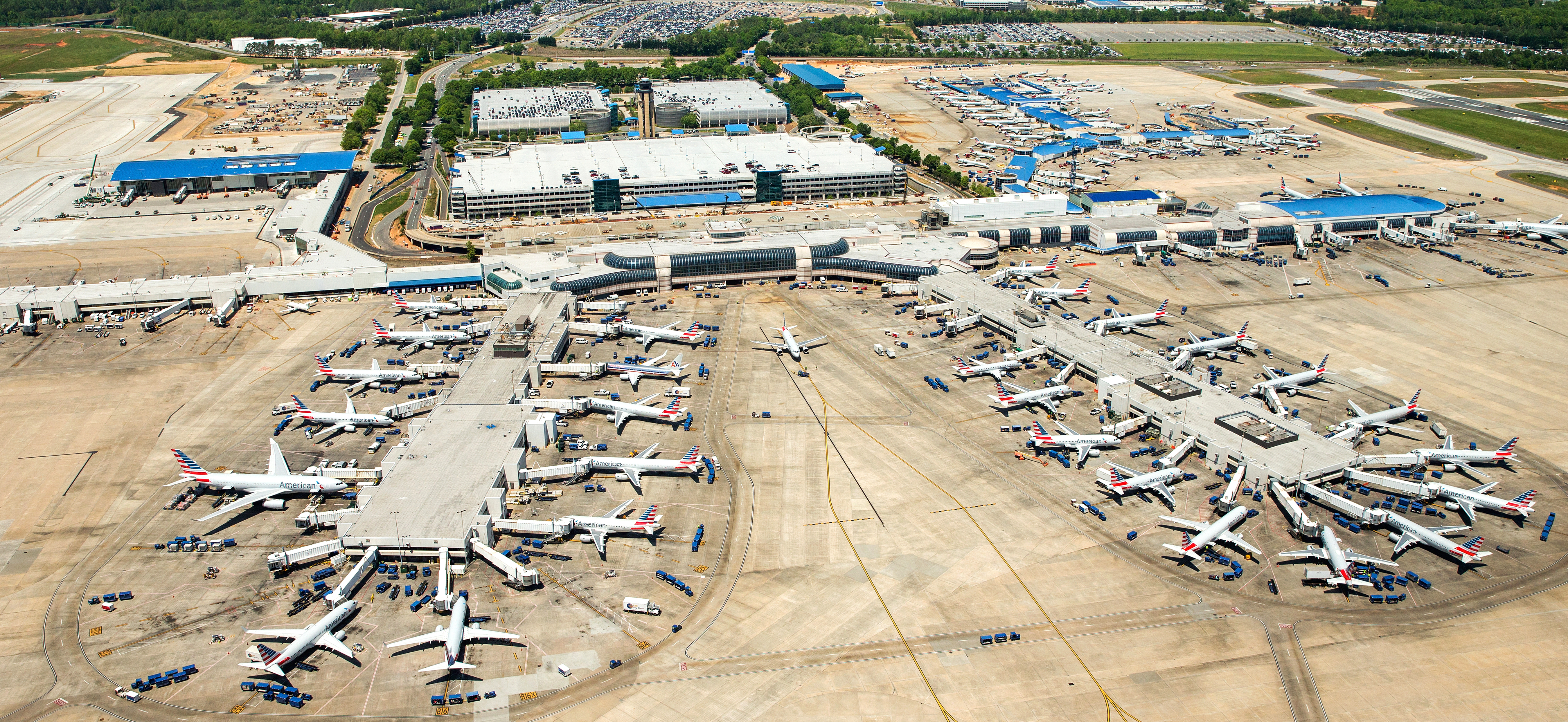 Aerial shot of the outside view of CLT airport concourses, planes are parked at various gates preparing for landing or take off.