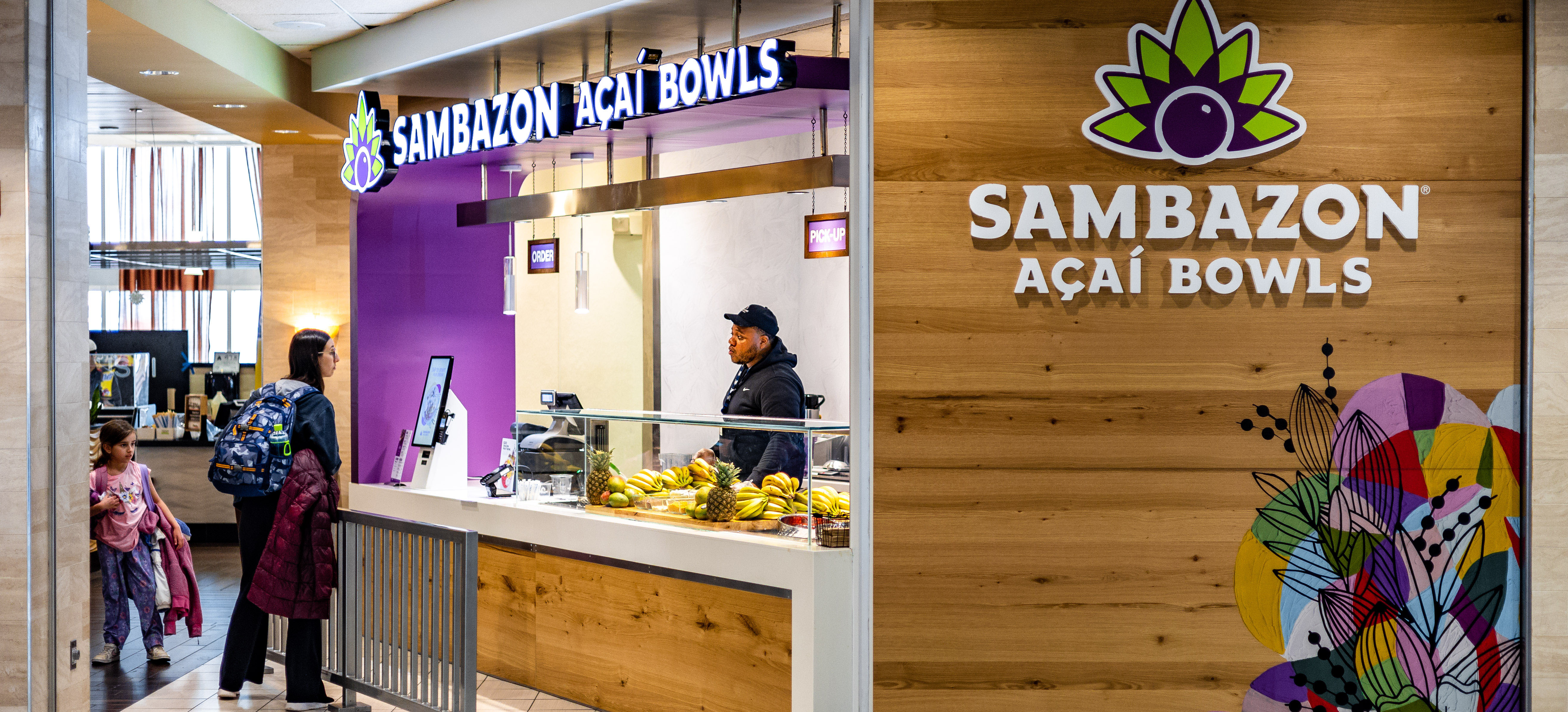 Sambazon Acai Bowls storefront in CLT Airport, employees and passengers are engaging at front counter