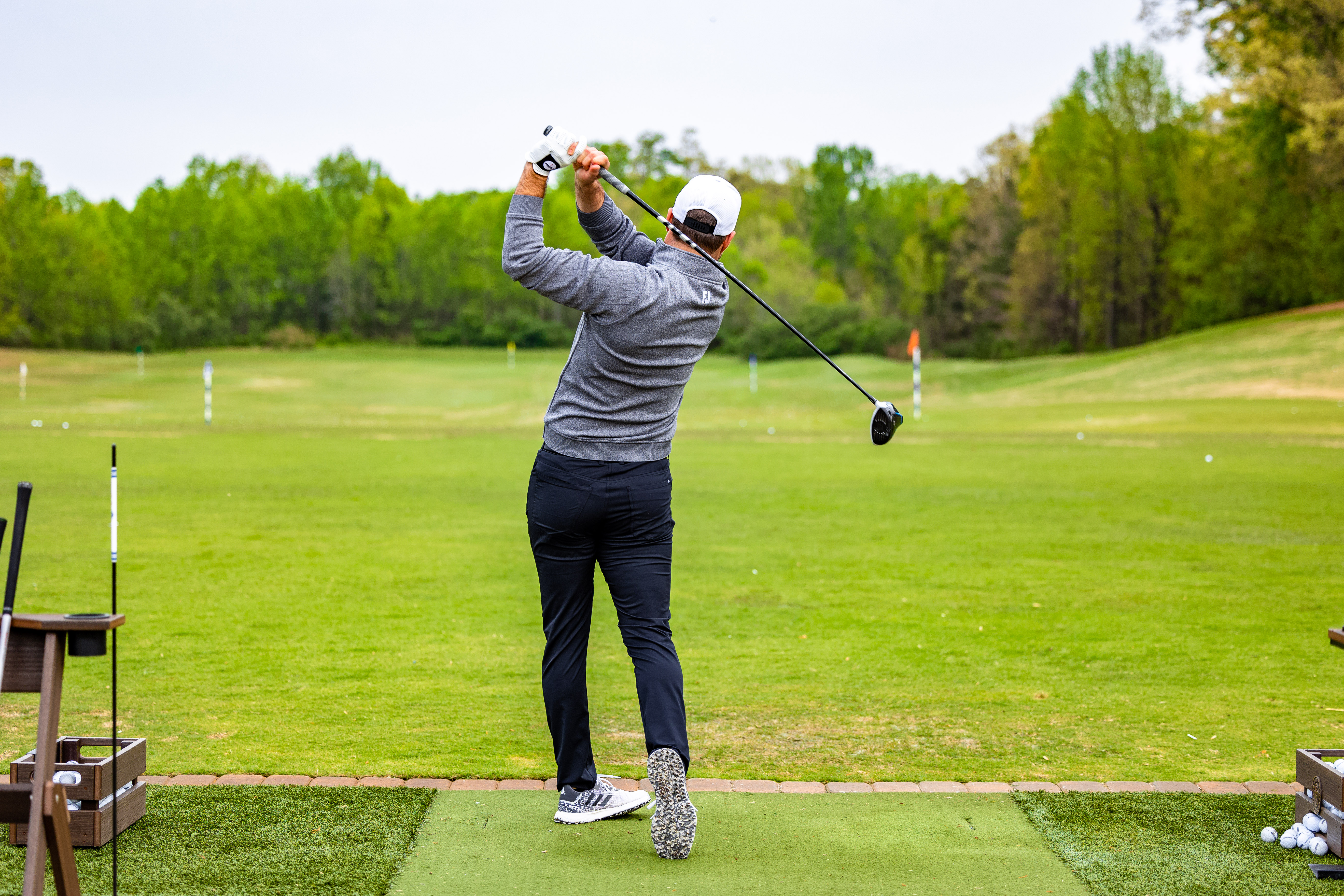 a person pictured from the back in full swing golf pose on golf course