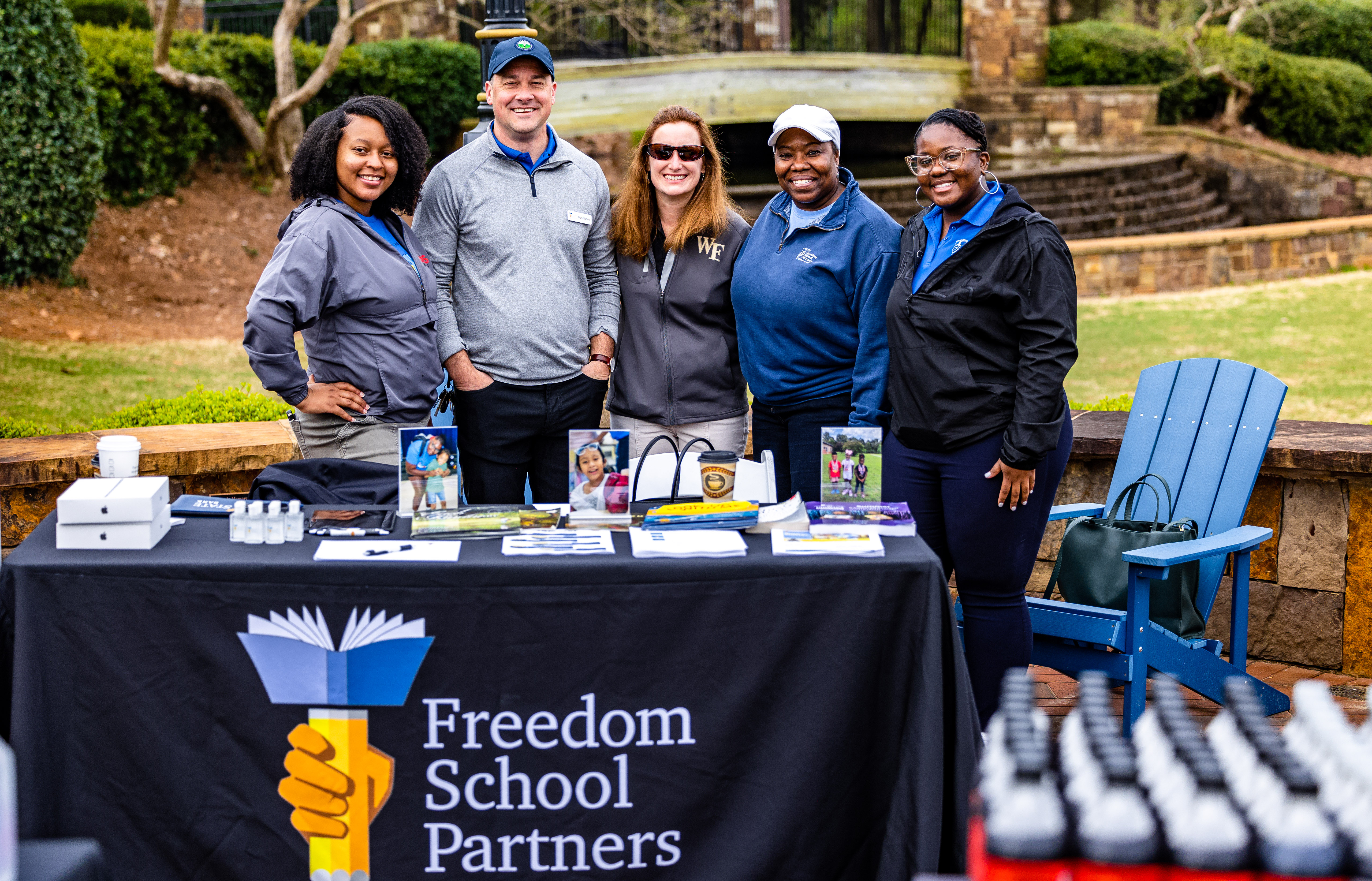 individuals from Freedom School Partners smiling big at vendor table with swag bag items