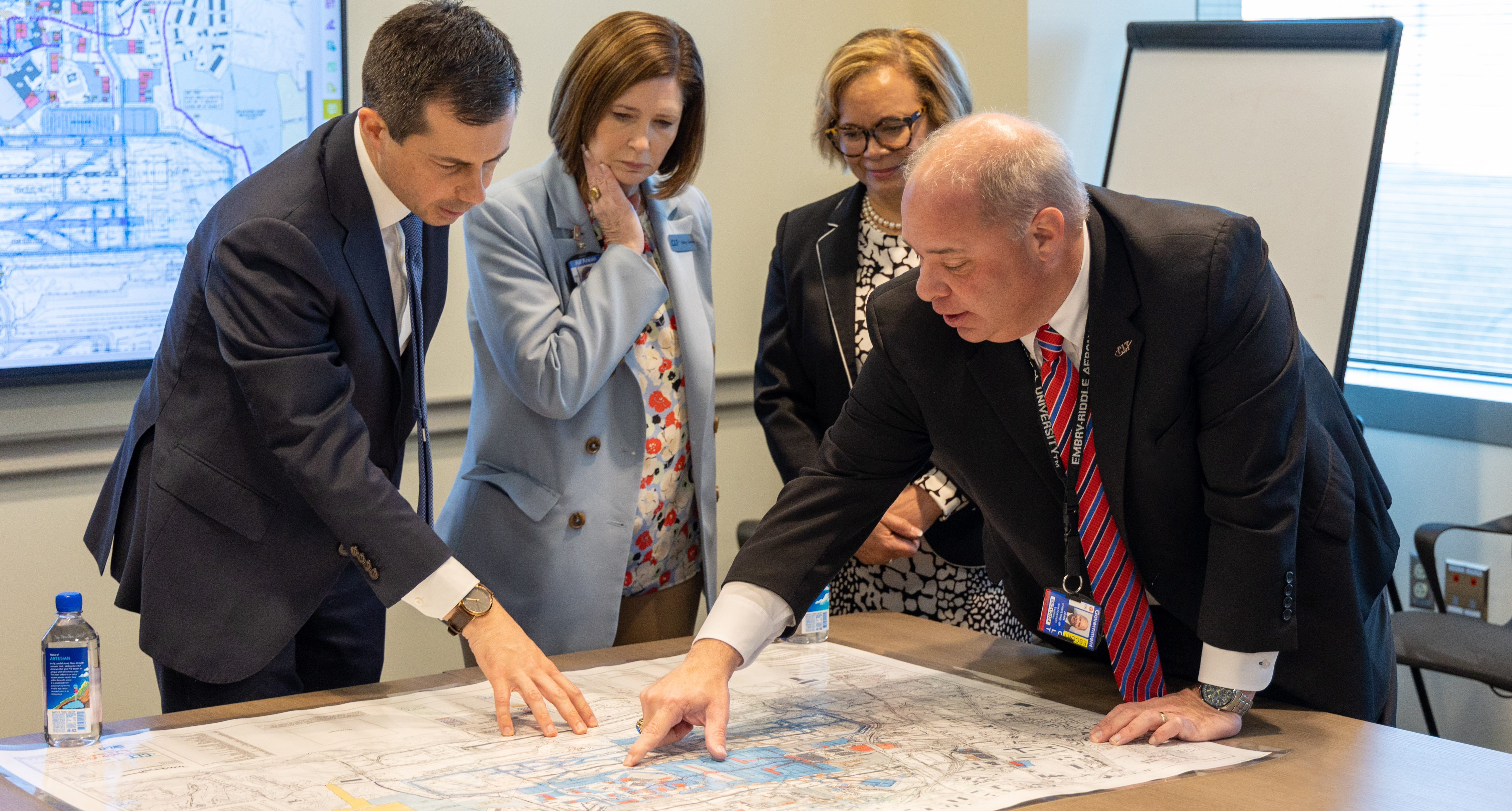 Aviation leadership team, mayor, and US Department of Transportation Secretary pointing and viewing a map of operational safety and airfield investment  