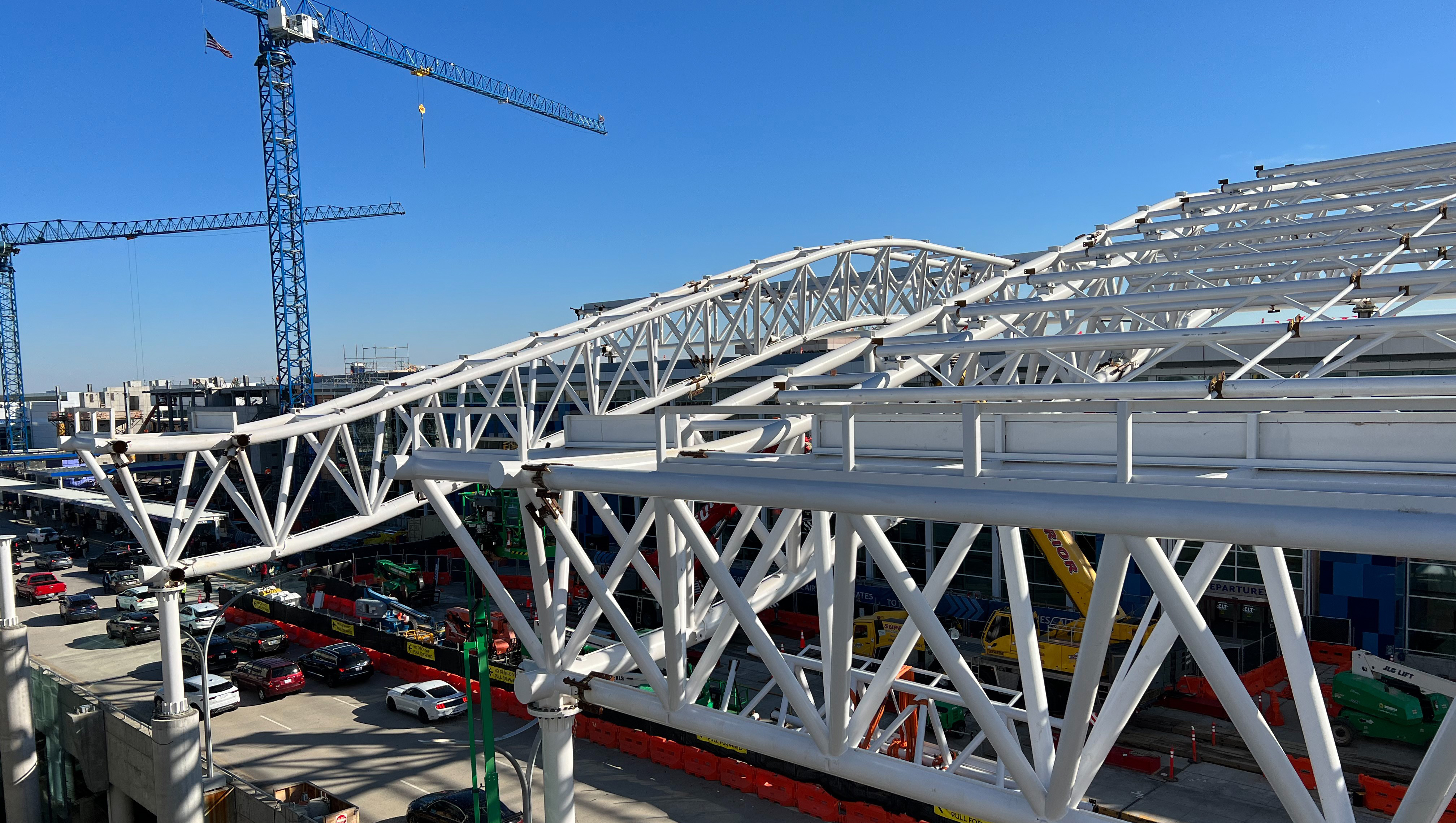  Terminal canopy installation over upper roadway, white canopy with cranes and vehicle traffic 